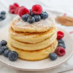 pancakes impilati su un piatto con sopra dei frutti di bosco
