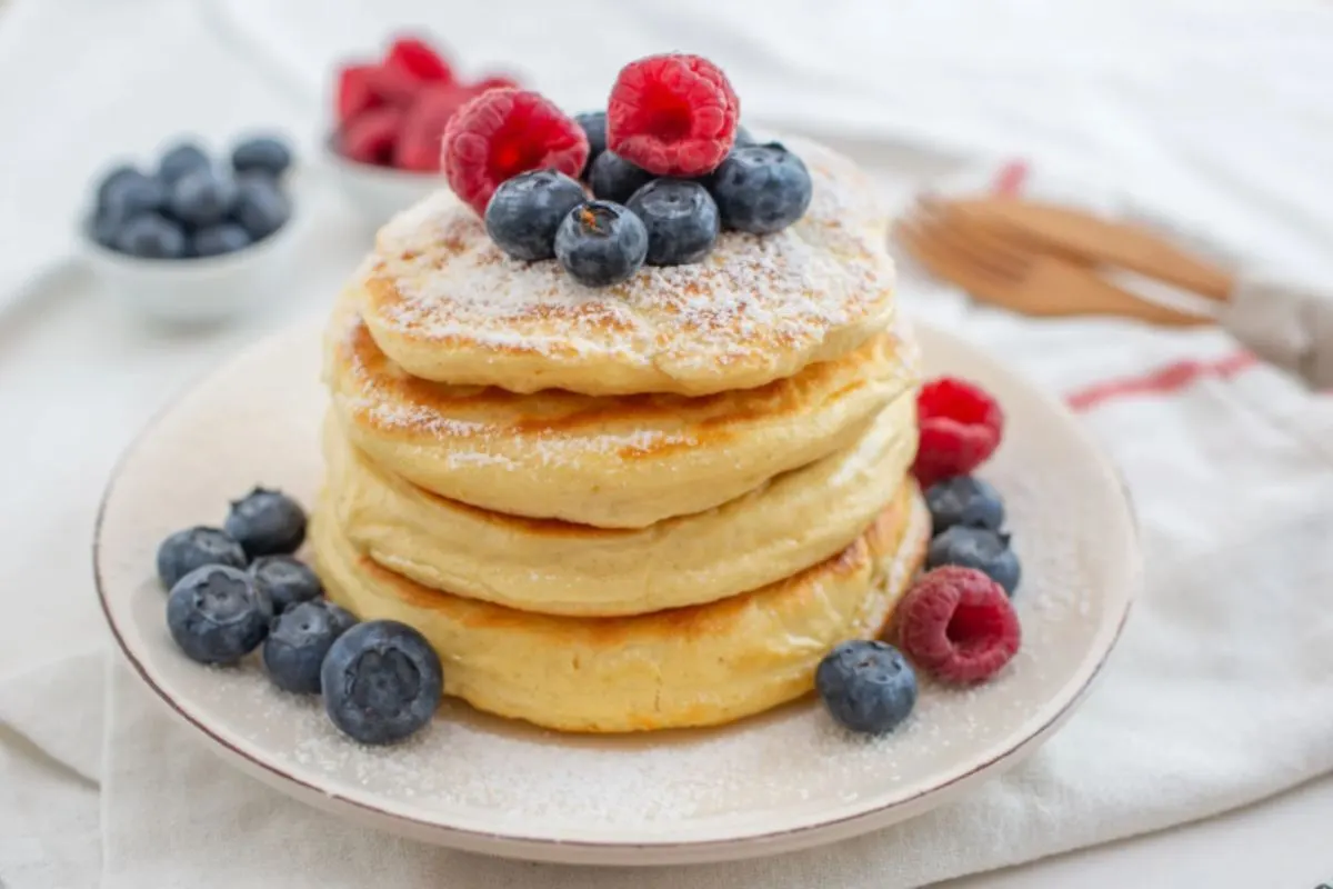 pancakes impilati su un piatto con sopra dei frutti di bosco