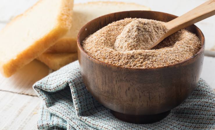 Ciotola con pangrattato e fette di pane accanto