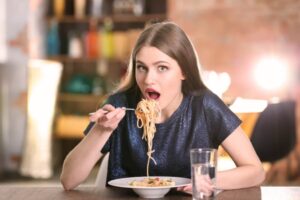 donna seduta al tavolo che mangia un piatto di spaghetti