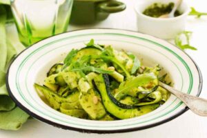tagliatelle di zucchine condite con il pesto e sopra delle foglie di rucola