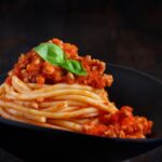spaghetti al sugo dentro ad un piatto nero