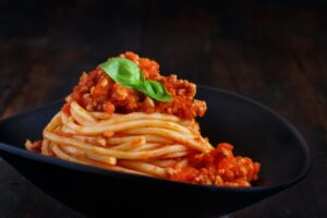 spaghetti al sugo dentro ad un piatto nero