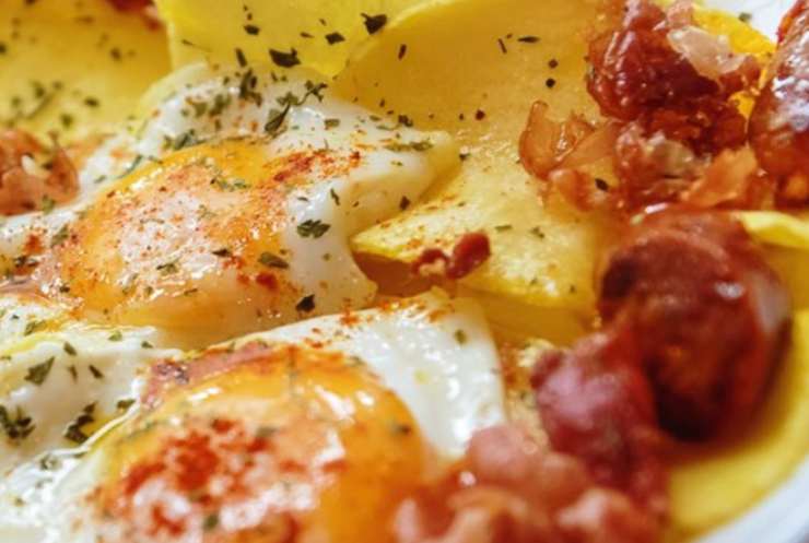 piatto di patate con pancetta e uovo cotto