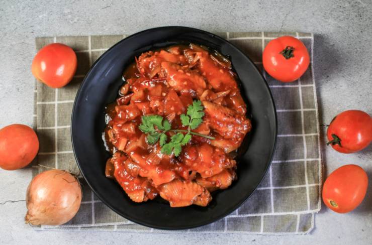 peperonata con intorno dei pomodori e una cipolla