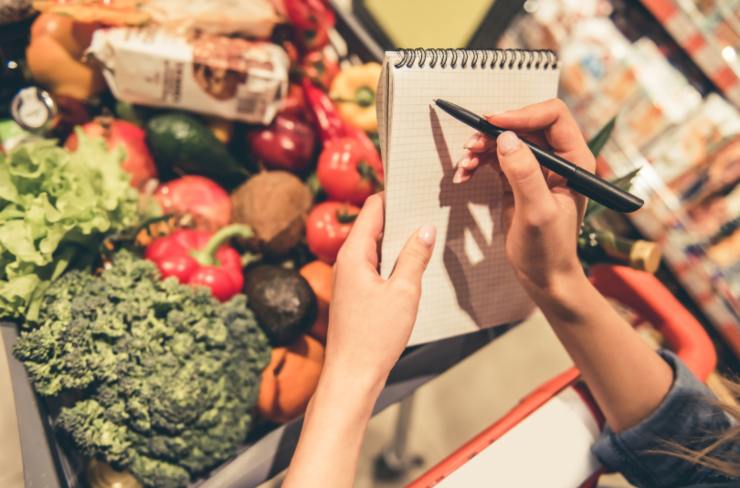 donna al supermercato che scrive qualcosa su un block notes