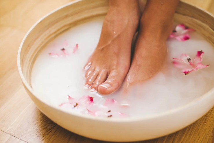 donna con i piedi immersi in una bacinella con dei fiori