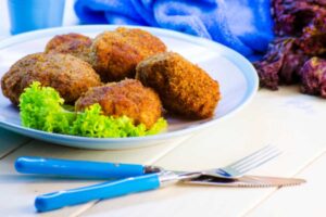 polpette fritte su un piatto con accanto dell'insalata e vicino delle posate