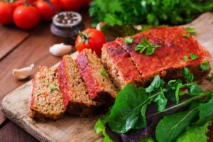 polpettone su un tagliere con accanto verdure e aglio