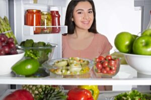 donna che apre il frigo pieno di ortaggi