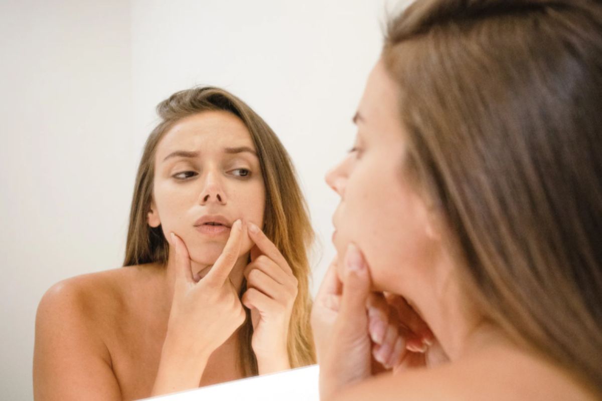 donna che si guarda allo specchio e strizza i punti neri