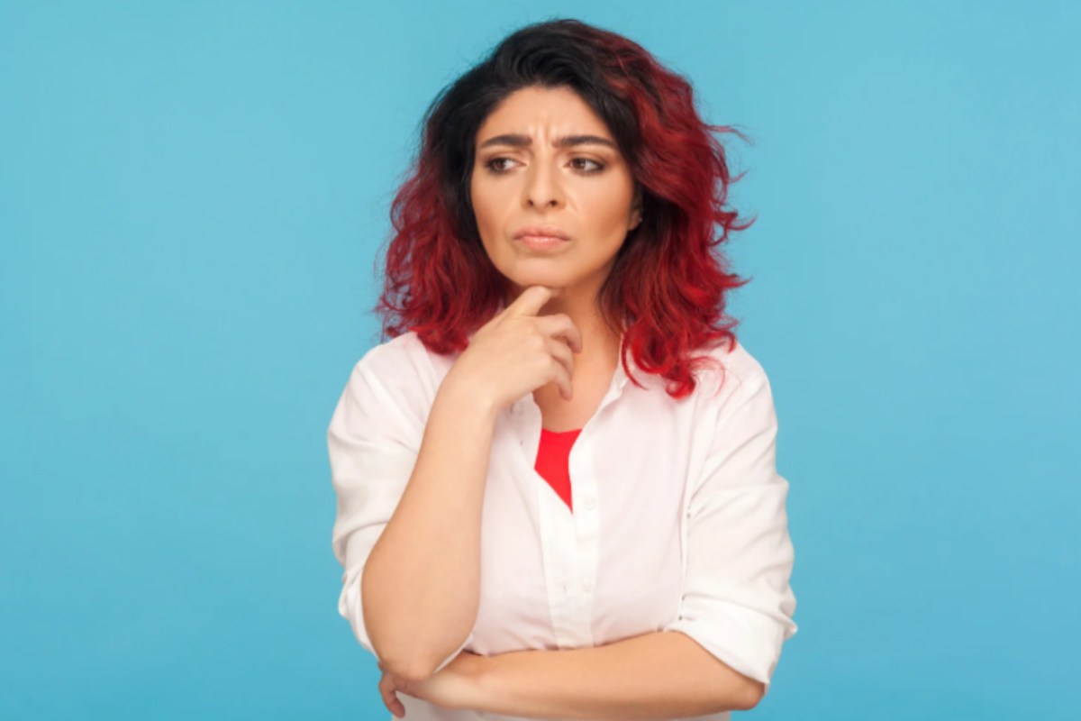 donna con espressione dubbiosa con un dito sotto al mento