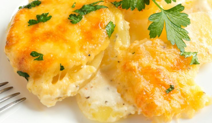 Patate schiacciate con all'interno formaggio e sopra foglie di prezzemolo