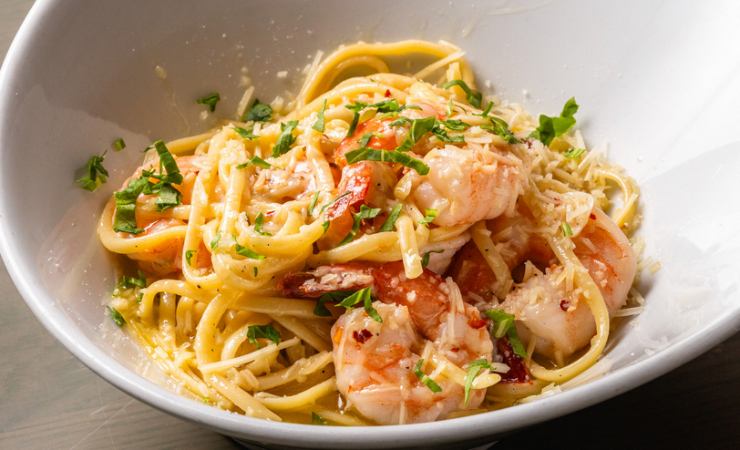 Piatto con linguine cotte cremose, erbe aromatiche, salsa e pomodori