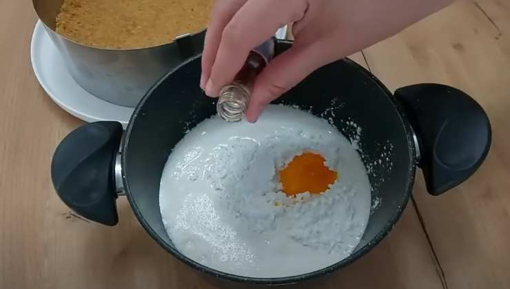 mano versa flacone in una padella