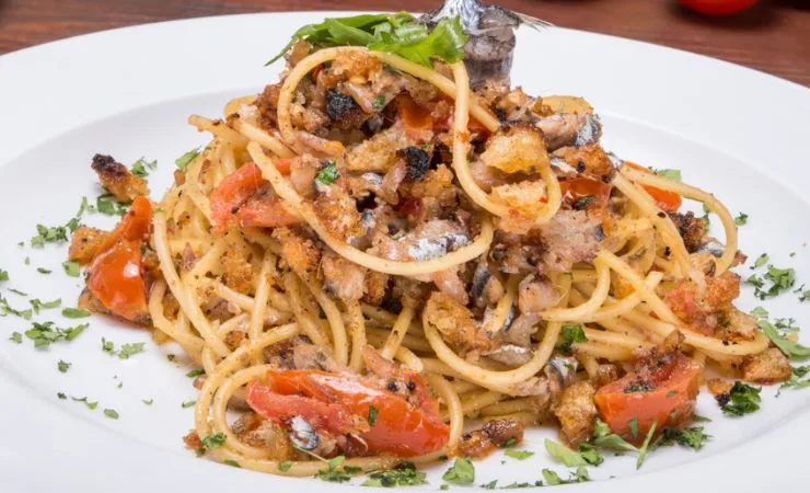Piatto di spaghetti con pomodorini, tonne, acciughe ed erbe aromatiche