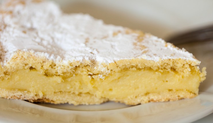 Fetta di torta in un piatto, con zucchero a velo e crema