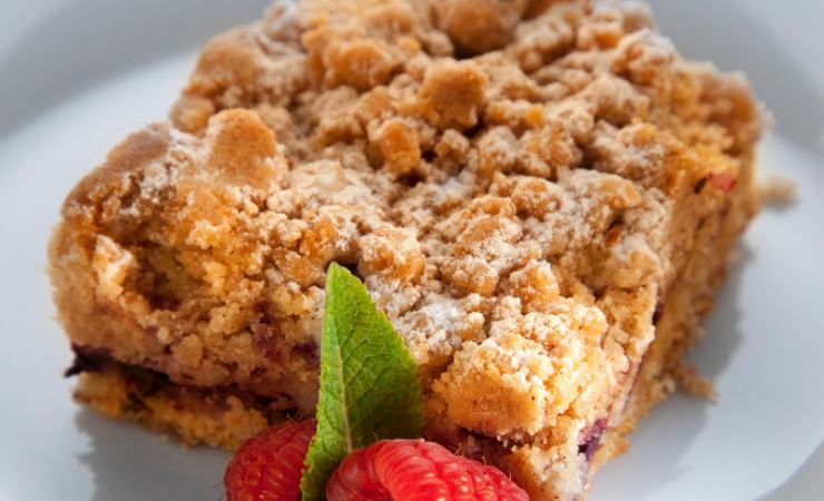 Pezzo di torta farcita con marmellata e lamponi vicino
