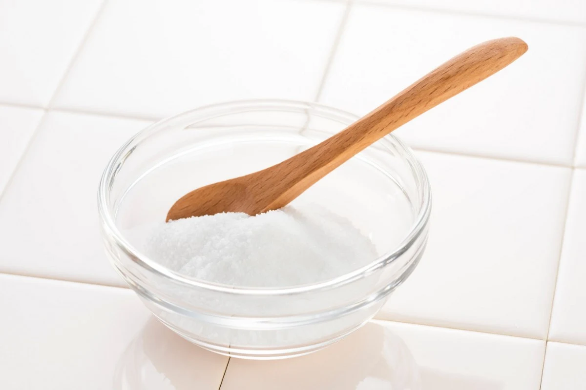 Ciotola con acido citrico in polvere e cucchiaio in legno