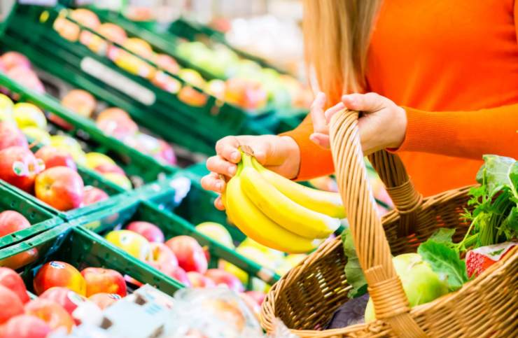 donna che mette la frutta nel cestino della spesa