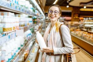 donna che sorride al supermercato con in mano una bottiglia di latte