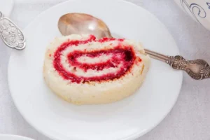 Fetta rotolo farcito con marmellata ai lamponi in un piatto