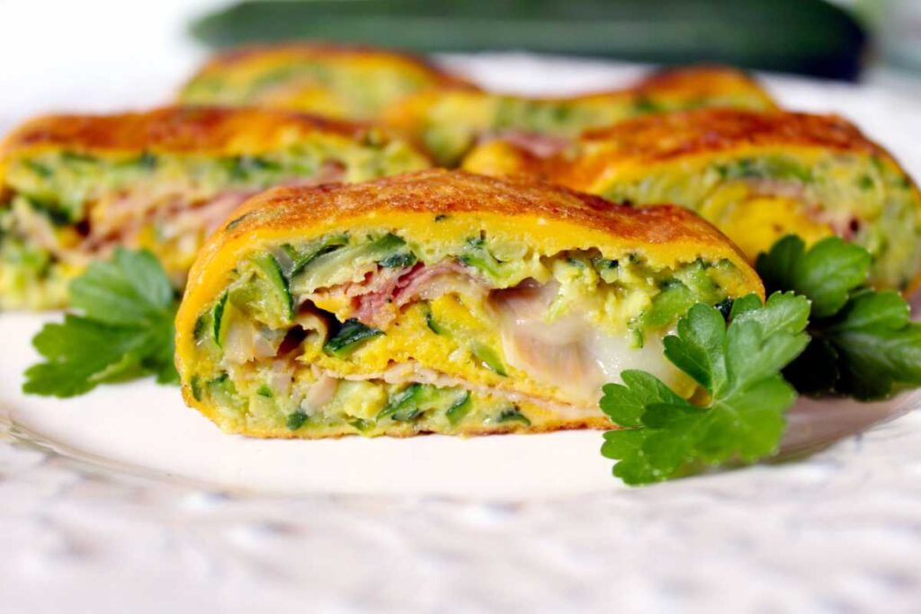 Rotolo di frittata tagliato con prosciutto cotto, zucchine e formaggio