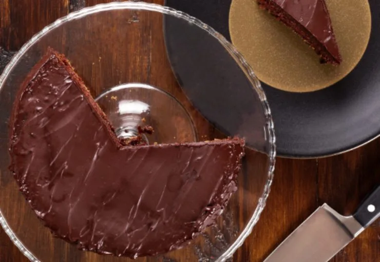 torta sacher sopra un'alzatina per dolci e accanto una fetta su un piatto