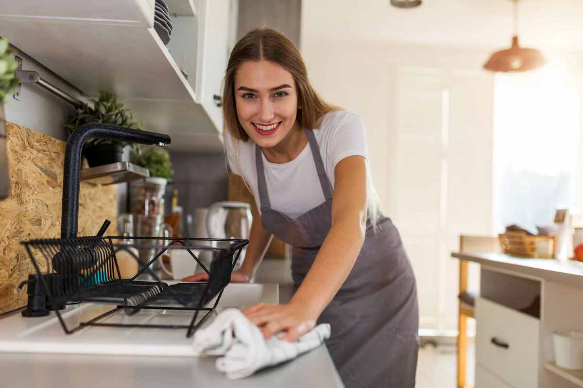 Donna sorridente che pulire la cucina con un panno