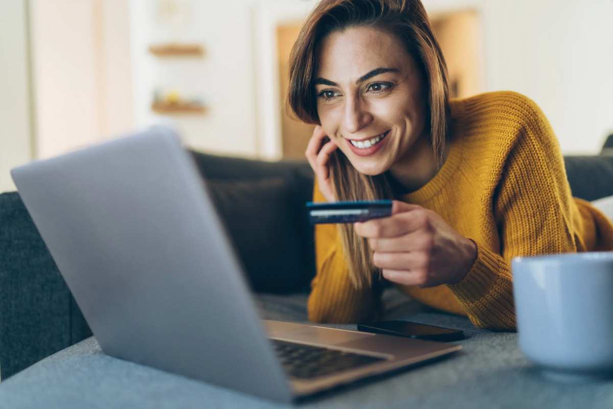 Donna che sorride davanti al pc con carta in mano