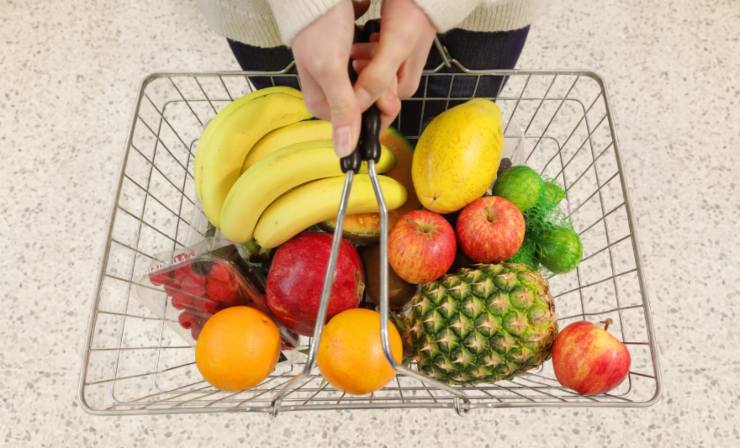 persona che tiene in mano un cestino pieno di frutta