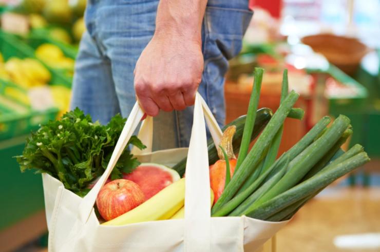 uomo con in mano una borsa piena di ortaggi