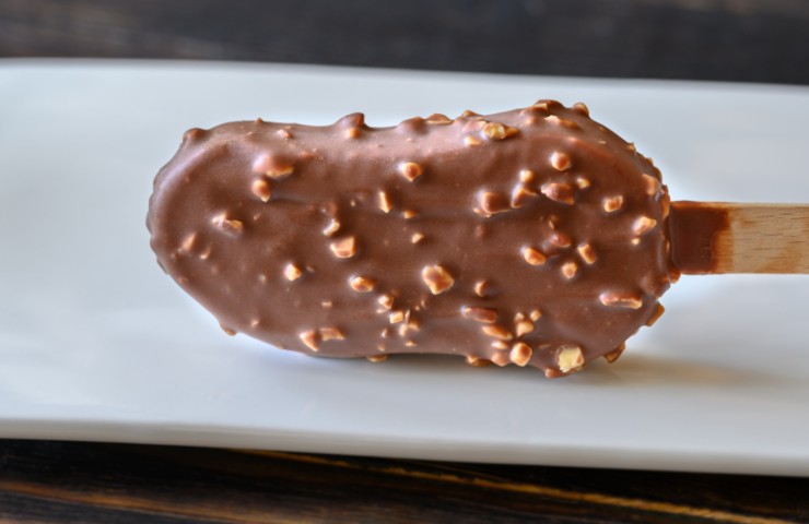 stecco gelato ricoperto di cioccolato e noccioline su un piatto