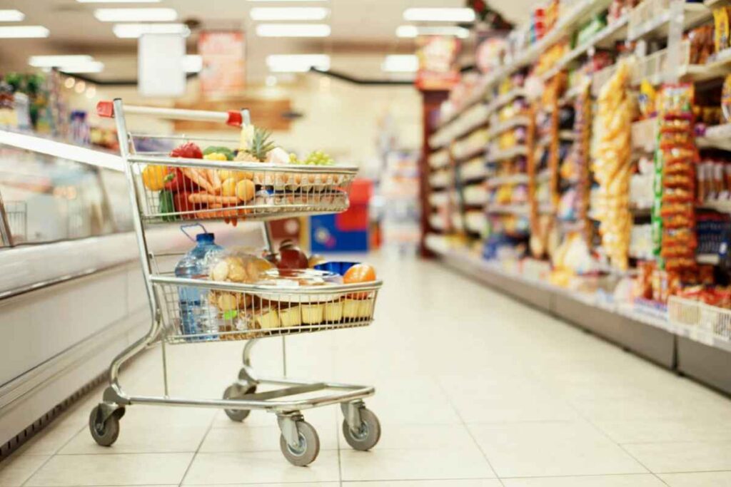 Carrello pieno tra gli scaffali di un supermercato