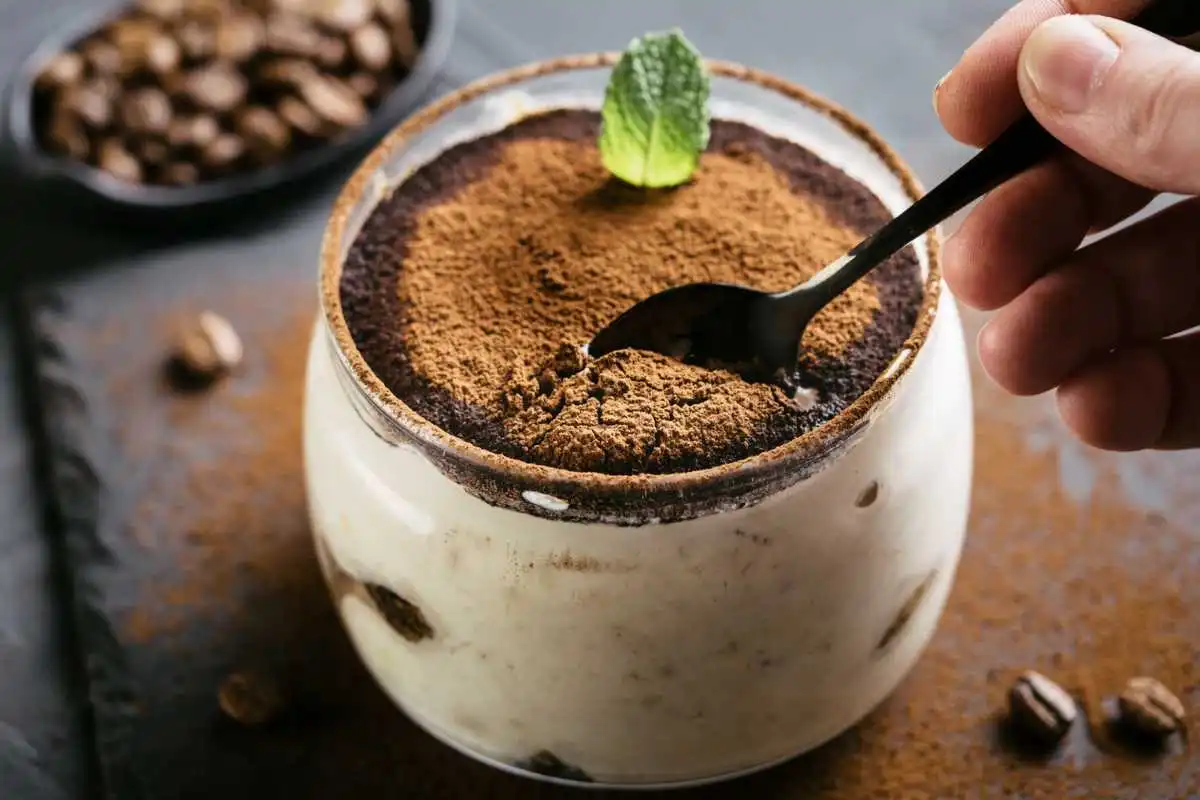 Tiramisù in un bicchiere con polvere di cacao e un cucchiaino all'interno