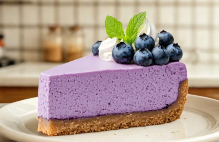 fetta di torta ai mirtilli con sopra mirtilli, menta e un po' di panna montata