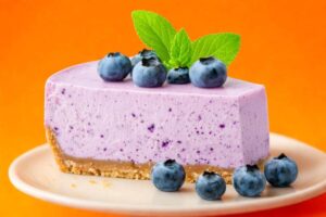 etta di torta ai mirtilli sopra ad un piatto con sopra mirtilli e qualche foglia di menta