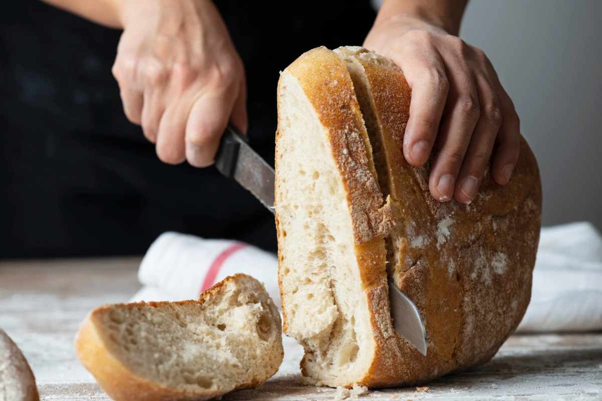 Persona che taglia il pane a fette