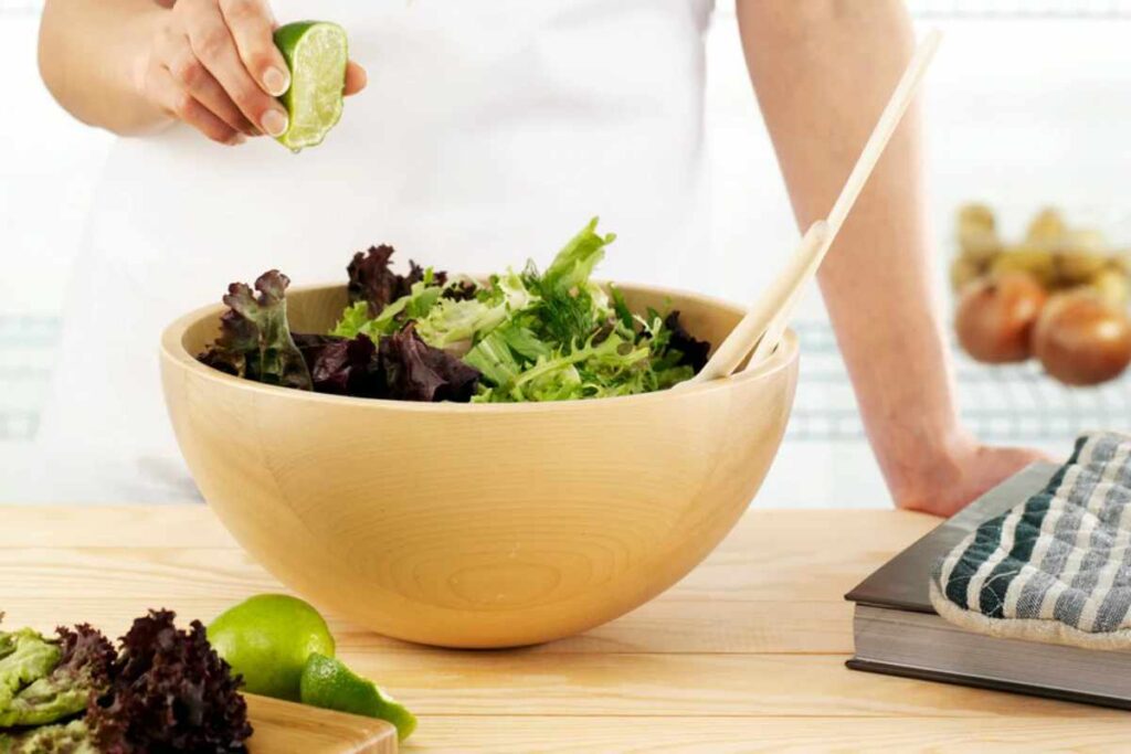Donna che spreme limone in una ciotola con insalata