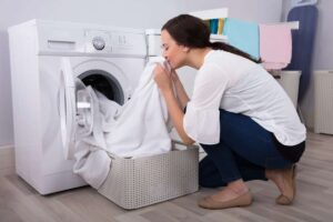Donna che annusa il bucato tirato fuori dalla lavatrice