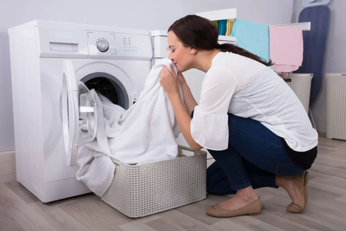 Donna che annusa il bucato tirato fuori dalla lavatrice