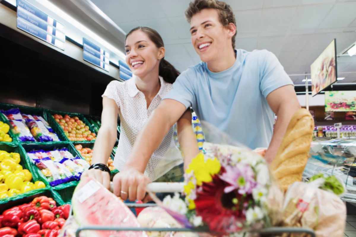 uomo e donna al supermercato con un carrello pieno di cibo