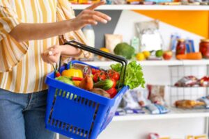 donna che fa la spesa con un cestino pieno di ortaggi