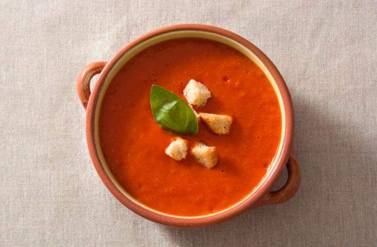 scodella di zuppa al pomodoro con sopra del basilico e dei crostini