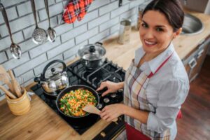 donna che cucina delle verdure in padella