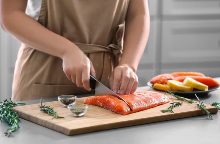 donna che taglia a pezzi un filetto di salmone