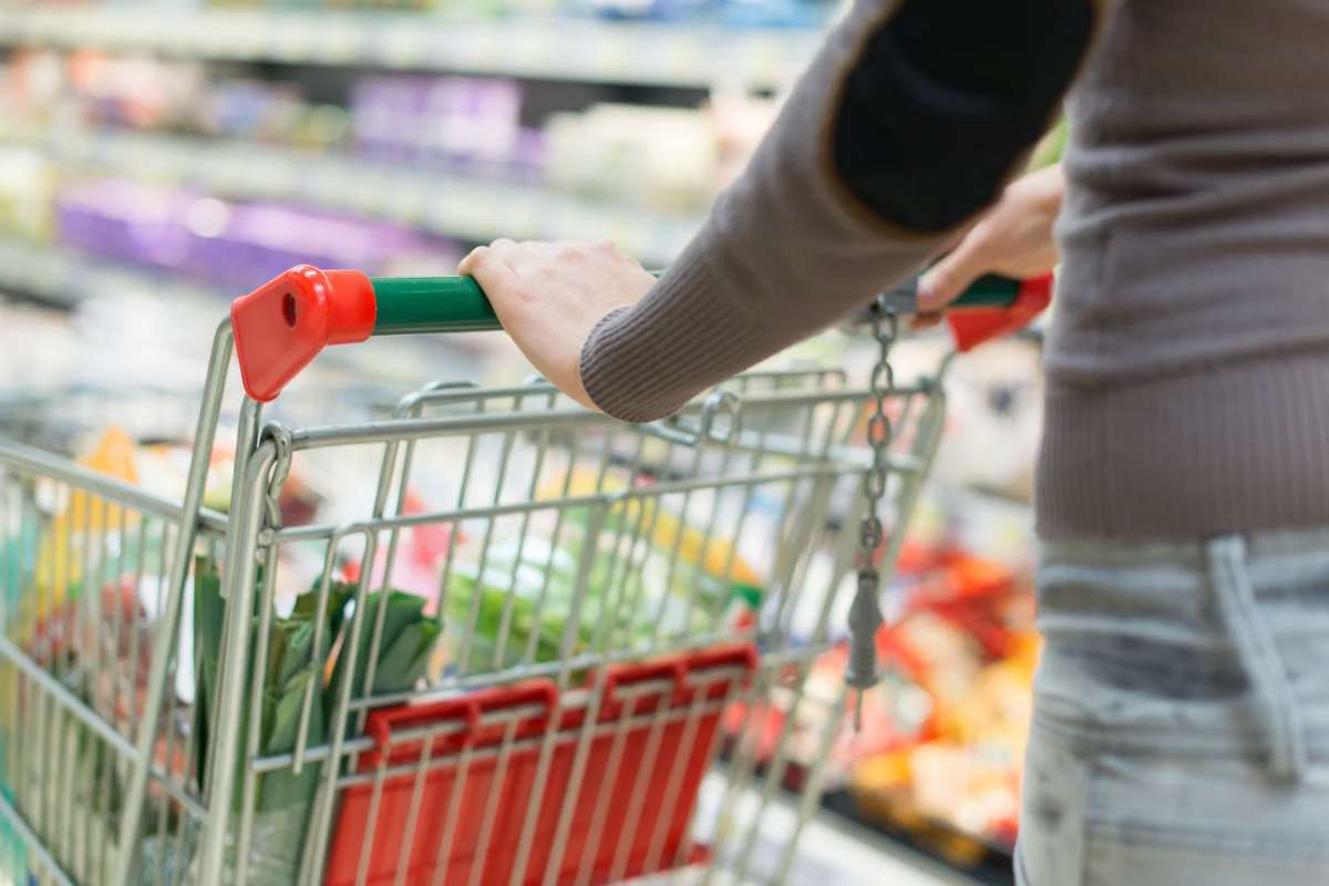 Donna che spinge carrello pieno in un supermercato