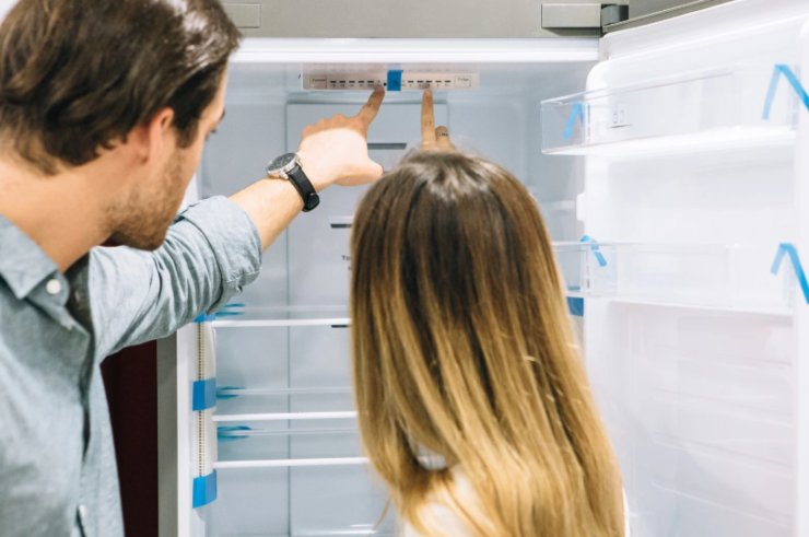 uomo e donna che guardano l'interno di un frigo