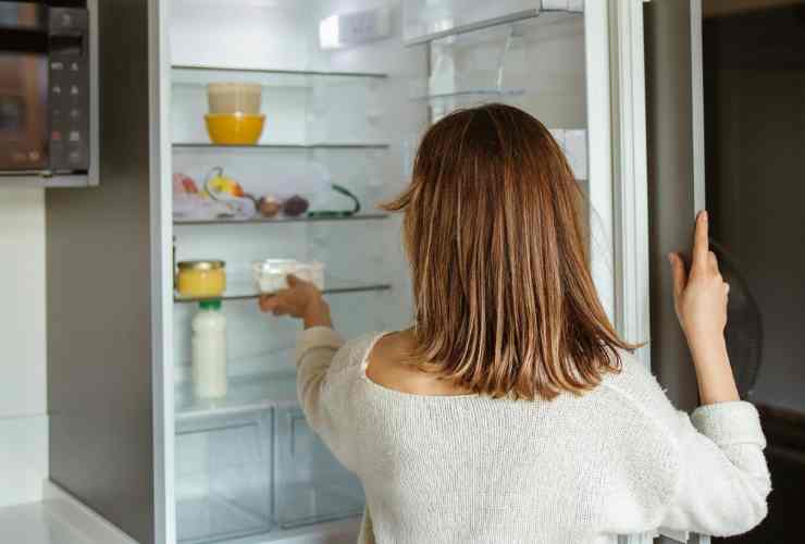 donna di spalle che guarda in frigorifero