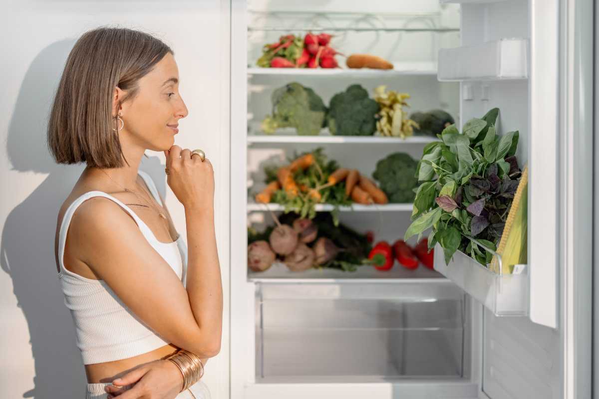 donna guarda il frigo aperto